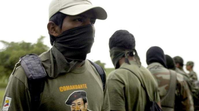 In this Monday, June 23, 2008, file photo, a member of the Revolutionary Armed Forces of Colombia, FARC stands with his face covered at a military base in Cali, Colombia. (AP Photo/Christian Escobar Mora)