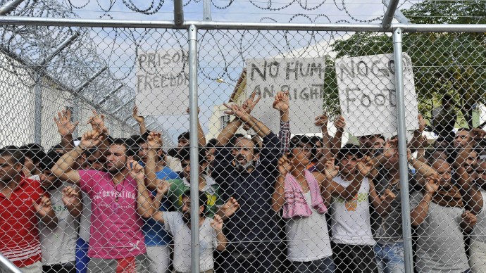 In this Monday, Oct. 8, 2012 file photo illegal immigrants hold signs behind a fence at a detention center in Komotini town, northern Greece. (AP Photo/Nikolas Giakoumidis, File)