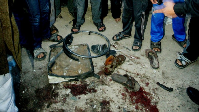 In this March 22, 2004, file photo, Palestinians gather around a pool of blood and the remains of the wheelchair of Hamas spiritual leader Sheikh Ahmed Yassin, following an Israeli air strike that killed him, near his house in Gaza City. Israel is considering resuming its contentious practice of assassinating militant leaders in the Hamas-ruled Gaza Strip in an effort to halt intensified rocket attacks on Israel's south, according to defense officials. (AP Photo/Kevin Frayer, File)