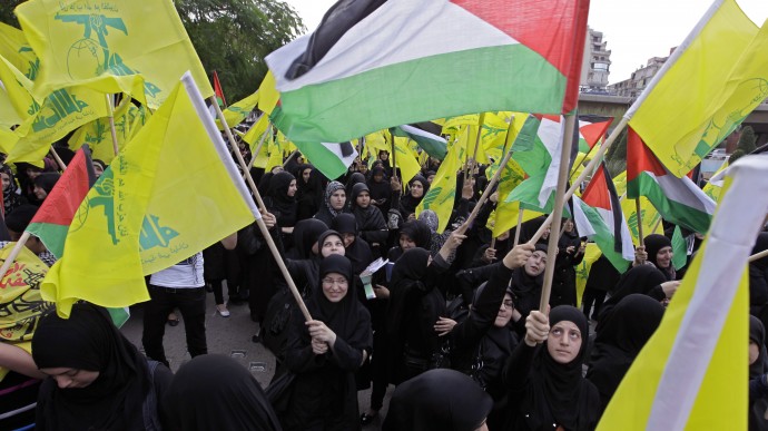 In this photo taken on Saturday, Nov. 17, 2012, Hezbollah supporters wave Hezbollah and Palestinian flags during a demonstration against the Israeli offensive in Gaza. (AP Photo/Bilal Hussein)