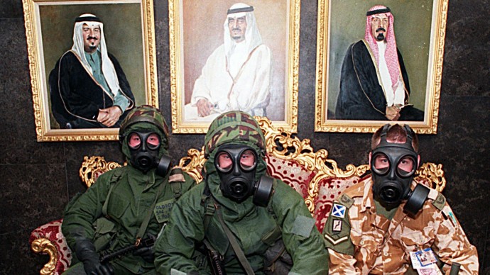 Three British soldiers, wearing chemical and biological protective gear, sit in front of portraits of members of the Saudi royal family in a hotel lobby while waiting for the all-clear siren during a Scud missile alert in Dhahran, Saudi Arabia, during the Persian Gulf War in this February 26, 1991 photo. (APPhoto/J. Scott Applewhite)