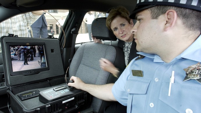 Chicago police officer Brian Berkowitz, right, shows Chicago Alderman Giner Rugai, center, how a portable surveillance can be controlled within a patrol car by the use of a joystick connected to remote control devise, left, in Chicago. (APPhoto/Stephen J. Carrera)