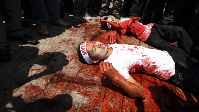 Covered in mock blood, Muslim protesters perform a die-in during a rally outside the embassy of Myanmar in Jakarta, Indonesia, Thursday, Aug. 9, 2012. Dozens of people staged the rally calling for an end to the violence against ethnic Rohingya Muslims in Rakhine State of Myanmar. (AP Photo/Dita Alangkara)