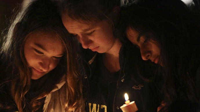 Kate Suba, left, Jaden Albrecht, center, and Simran Chand pay their respects at one of the makeshift memorials in honor of the victims of the Sandy Hook Elementary School shooting, Sunday, Dec. 16, 2012, in Newtown, Conn. (AP Photo/Mary Altaffer)