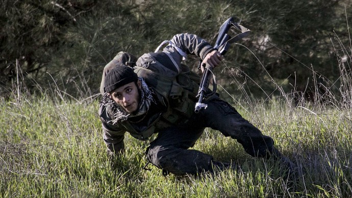 In this Saturday, Dec. 15, 2012 photo, a Free Syrian Army fighter takes cover during heavy clashes with government forces at a military academy besieged by the rebels north of Aleppo, Syria. (AP Photo/Narciso Contreras)