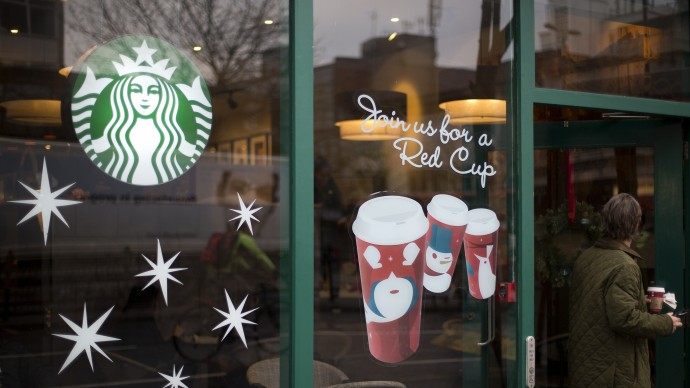 A man walks out of a Starbucks coffee cafe holding a drink in west  London, Monday, Dec.  3, 2012. (AP Photo/Alastair Grant)
