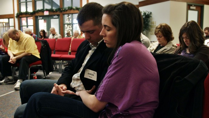 In this Dec. 23, 2012 photo, three weeks back home from the war in Afghanistan, U.S. Army 1st Lt. Aaron Dunn and his wife Leanne pray during services at their church, in Colorado Springs, Colo. (AP Photo/Brennan Linsley)