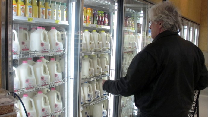 In this Dec. 4, 2012, file photo, Jim Mitchell selects a gallon of milk at a Milwaukee grocery store. (AP Photo/Dinesh Ramde, File)