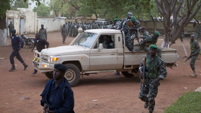 In this March 27, 2012 file photo, Malian soldiers loyal to coup leader Capt. Amadou Haya Sanogo secure the location as he arrives at his headquarters at Kati military base, just outside Bamako. (AP Photo/Rebecca Blackwell, File)