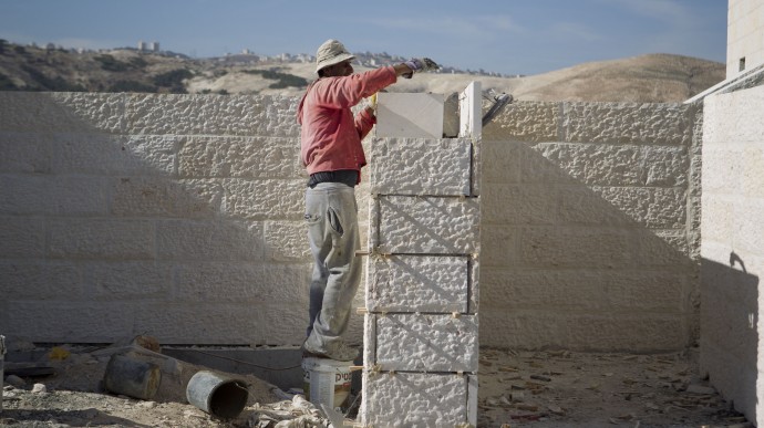 A Palestinian man works at a new housing development in the Jewish West Bank settlement of Maaleh Adumim, near Jerusalem, Sunday, Dec. 2, 2012. (AP Photo/Ariel Schalit)