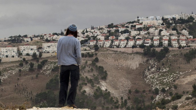 A Jewish settler looks at the West bank settlement of Maaleh Adumim, from the E-1 area on the eastern outskirts of Jerusalem, Wednesday, Dec. 5, 2012. (AP Photo/Sebastian Scheiner)