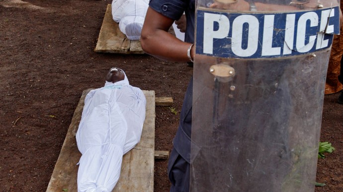 In this Friday, Oct. 2, 2009 file photo, a Guinean policeman stands guard beside the bodies of people killed during an opposition rally in Conakry, Guinea on Monday, Sept 28, 2009. A U.S.-based human rights group says the Sept. 28 massacre by Guinean troops of at least 150 people and the rapes of dozens of women at a pro-democracy rally in Guinea were premeditated, and that rapes of kidnapped women continued for days. (AP Photo/Schalk van Zuydam, File)