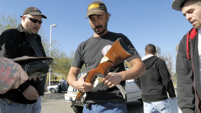 Gun buyers inspect their purchases outside a police station in Tucson, Ariz. on Tuesday, Jan 8, 2013. (AP Photo/Matt York)