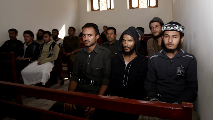 A Yemeni soldier, center, sits with suspected al-Qaida militants during their trial at a state security court in Sanaa, Yemen, Sunday, Jan. 6, 2013. (AP Photo/Hani Mohammed)