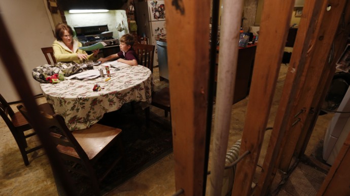 In this Thursday, Jan. 17, 2013 photo, seen through the beams of a gutted wall, Irene Sobolov, left, sits at a table while her 10-year-old son Joey Sobolov works on his fifth grade science homework in their home in Hoboken, N.J. (AP Photo/Julio Cortez)