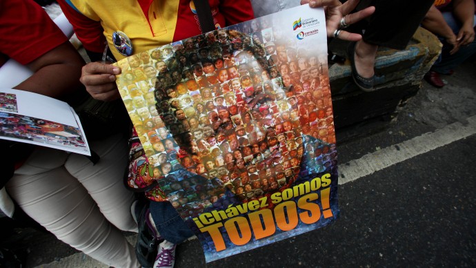 A supporter of Venezuela's President  Hugo Chavez holds poster of him with the slogan in Spanish "We are all Chavez!" at rally by Chavez supporters in Caracas, Venezuela, Wednesday, Jan. 23, 2013.  (AP Photo/Fernando Llano)