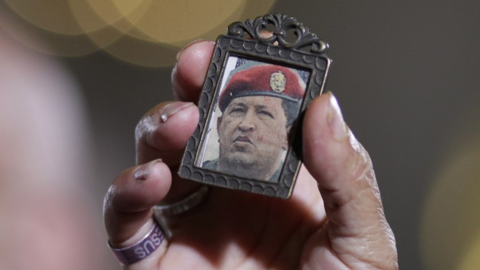 A woman holds up an image of Venezuela's President Hugo Chavez as people gather to pray for him at a church in Caracas, Venezuela, Monday, Dec. 31, 2012. (AP Photo/Ariana Cubillos)