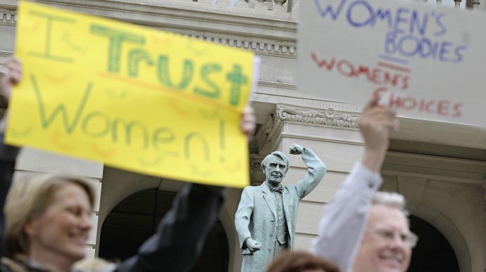 A statue of Thomas Watson, former Georgia politician who, in early years, fought for the working class, is seen as hundreds of people around the Georgia Capitol protest against two pieces of legislation they say are unfair to women Monday, March 12, 2012, in Atlanta. (AP Photo/David Goldman)