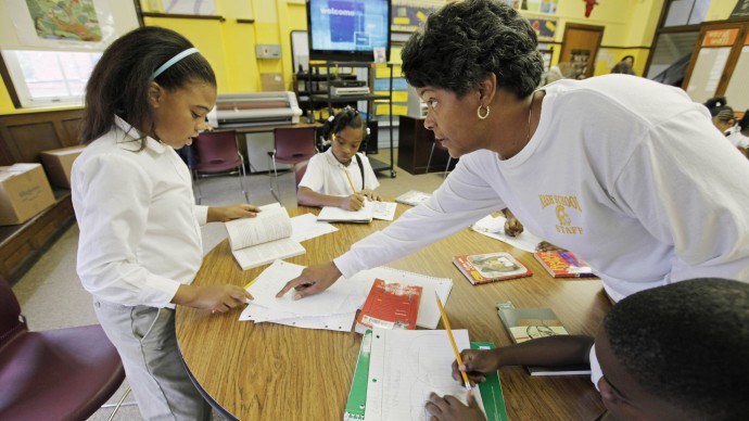 In this photo taken Sept. 28, 2011, Tresa Dunbar, principal of the Nash Elementary School, one of 13 schools where teachers voted to make the school day 90 minutes longer in exchange for extra pay, speaks to fourth-grader Daniyah Sanders in the school library in Chicago. (AP Photo/M. Spencer Green)